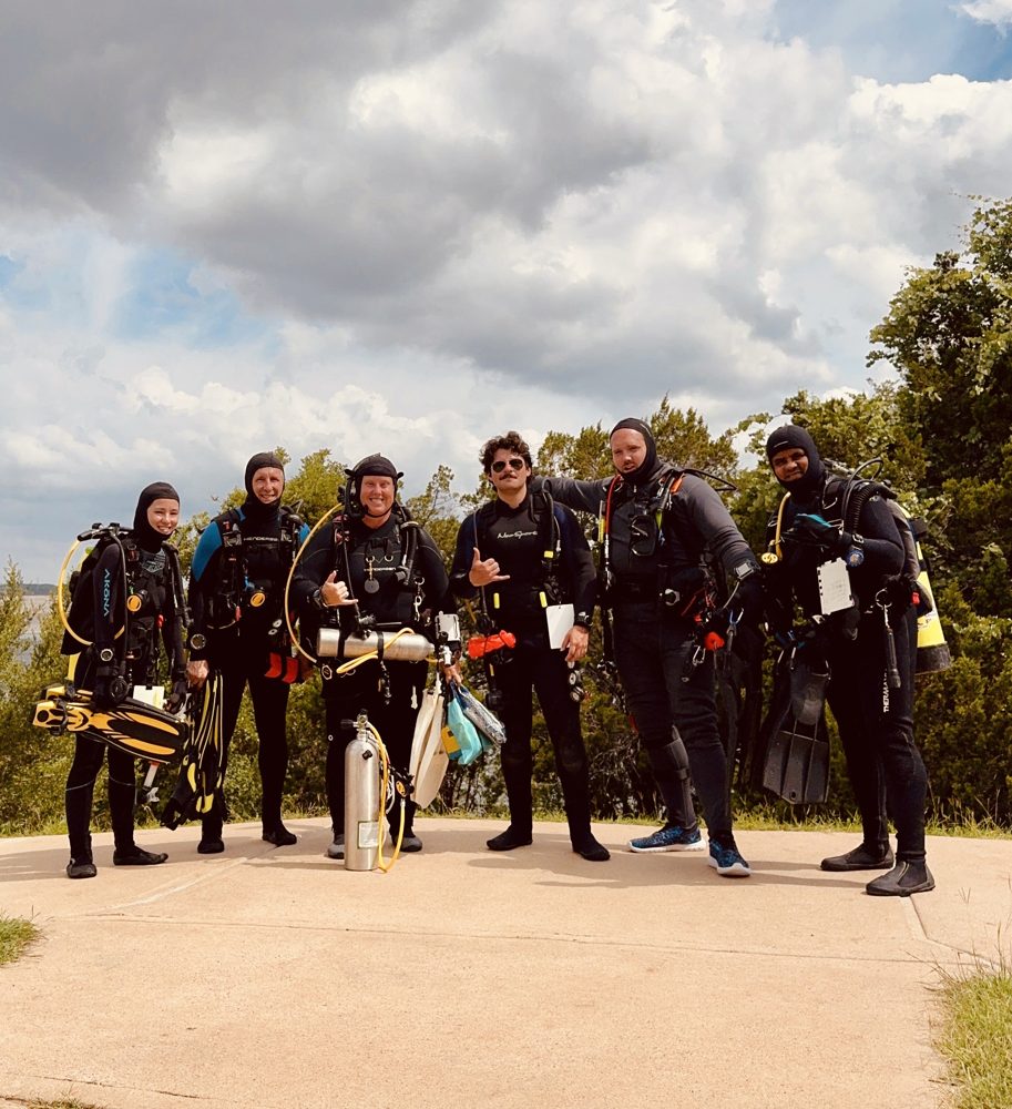 Me and a group of divers in full gear, smiling on the shore before a dive.