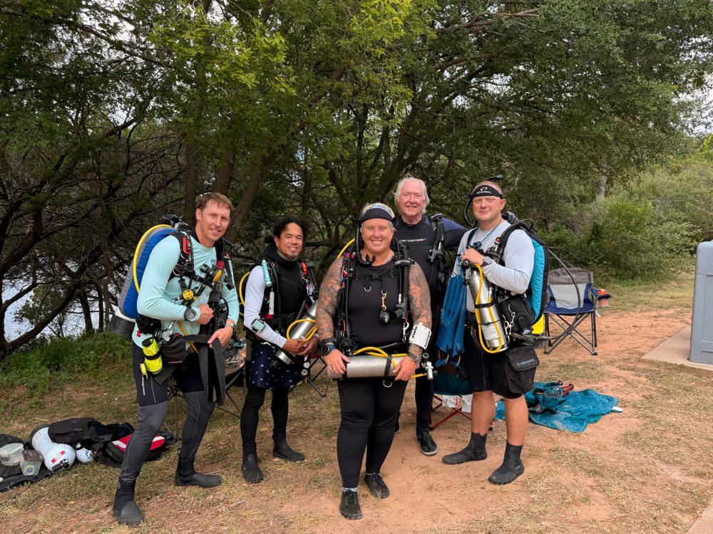 Me and four fellow divers in full gear at the lake, each carrying a backup tank.